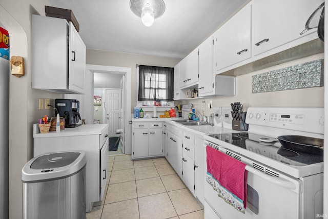 kitchen featuring light tile patterned floors, white range with electric cooktop, light countertops, white cabinets, and a sink