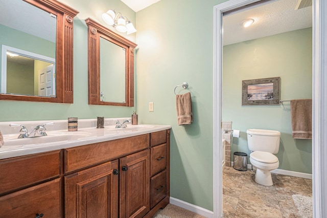 full bathroom featuring double vanity, a sink, toilet, and baseboards