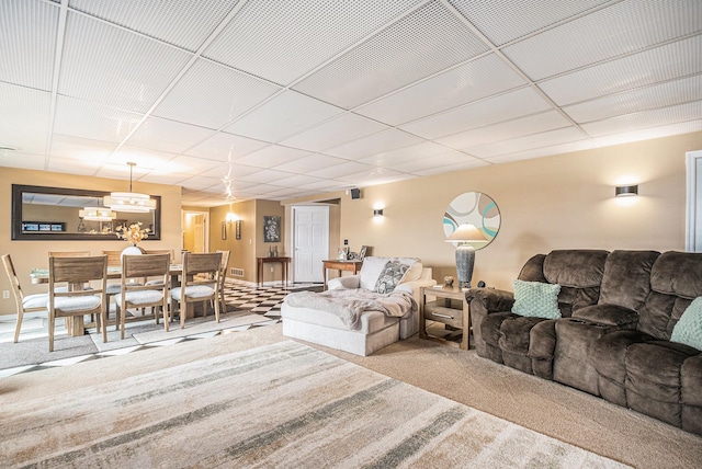 living area featuring a drop ceiling and carpet flooring