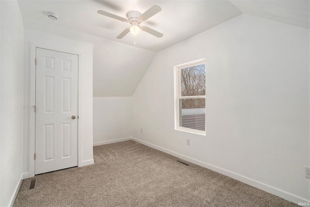 additional living space with light carpet, a ceiling fan, visible vents, vaulted ceiling, and baseboards