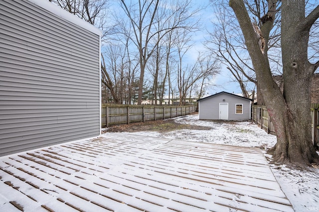 snow covered deck with an outbuilding and a fenced backyard