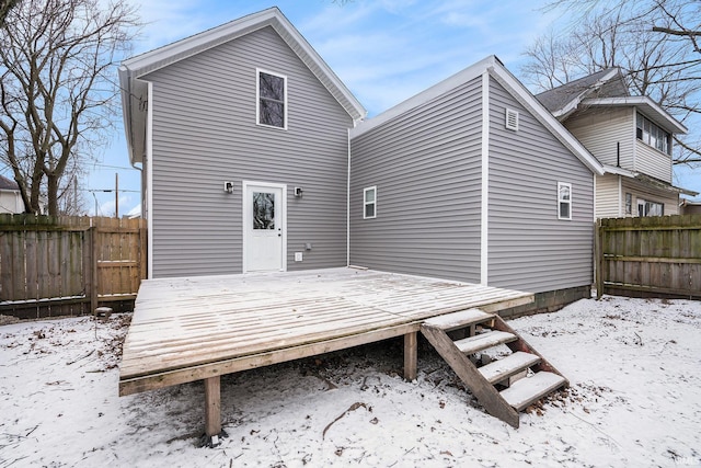 snow covered house featuring a deck and fence