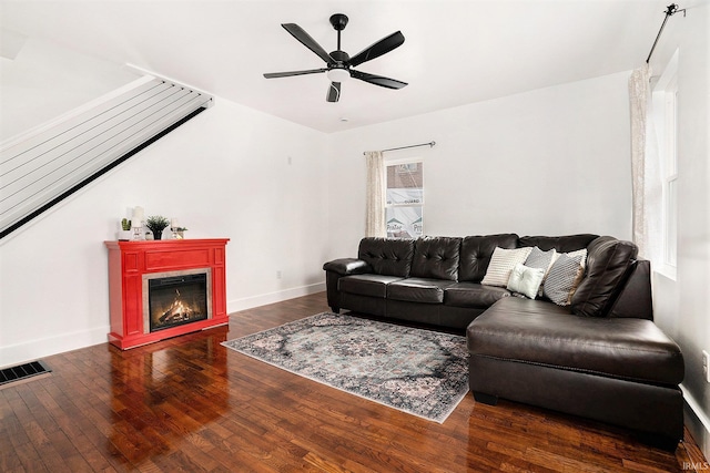 living room with baseboards, visible vents, a ceiling fan, a glass covered fireplace, and wood-type flooring