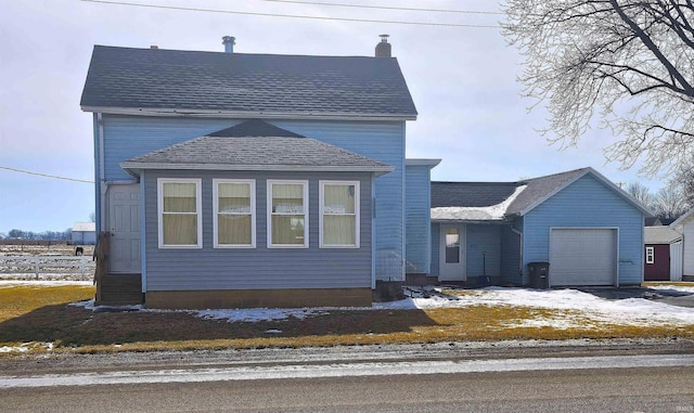 traditional-style home with a garage, roof with shingles, fence, and a chimney