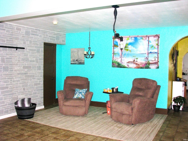 sitting room featuring baseboards, arched walkways, and a notable chandelier