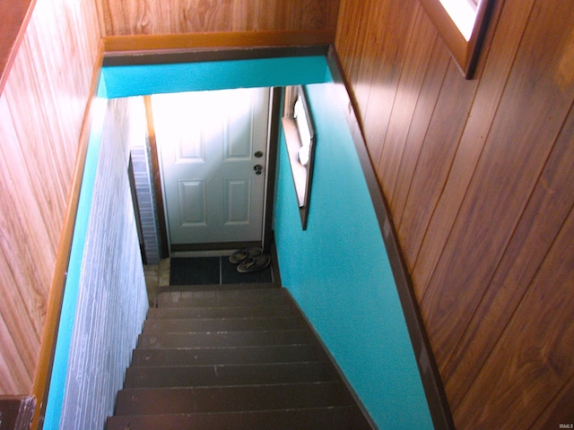 staircase featuring wooden walls