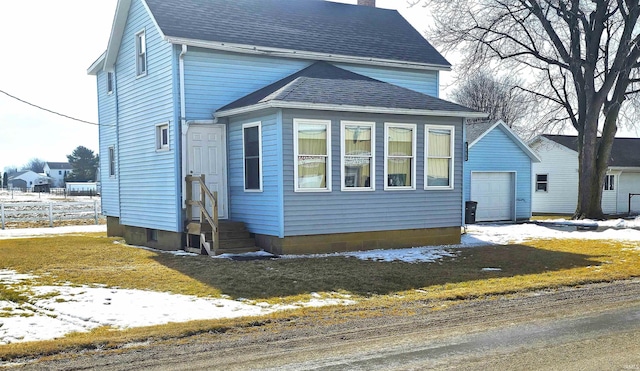 view of front facade with a garage, entry steps, roof with shingles, and a chimney