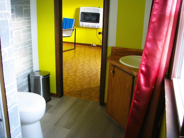 bathroom featuring parquet floors, heating unit, toilet, vanity, and baseboards