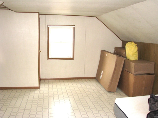 bonus room with light floors and vaulted ceiling