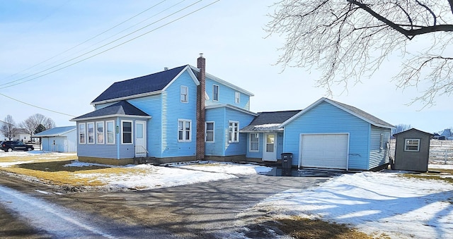 view of front of house featuring a garage, driveway, and a chimney