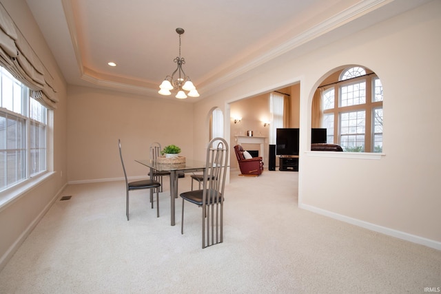 carpeted dining area with a fireplace, a notable chandelier, a raised ceiling, visible vents, and baseboards