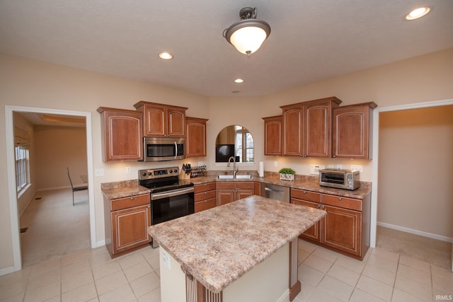 kitchen featuring arched walkways, a toaster, stainless steel appliances, a sink, and a kitchen island