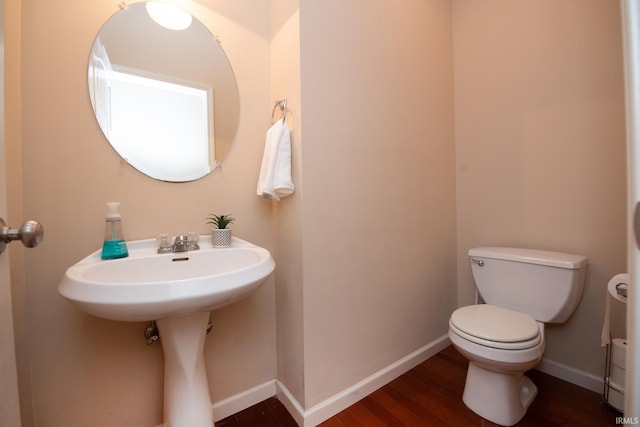 bathroom with toilet, baseboards, and wood finished floors