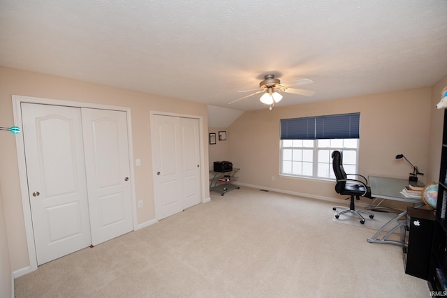 unfurnished office with baseboards, a ceiling fan, vaulted ceiling, a textured ceiling, and carpet floors