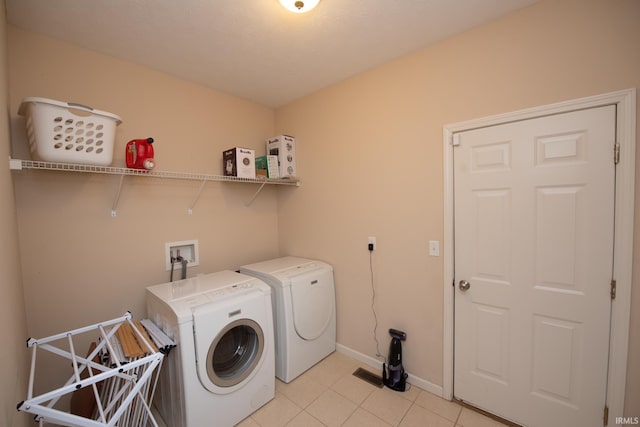 washroom featuring washer and dryer, laundry area, light tile patterned flooring, and baseboards