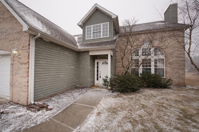 view of front facade featuring a garage, roof with shingles, a chimney, and brick siding