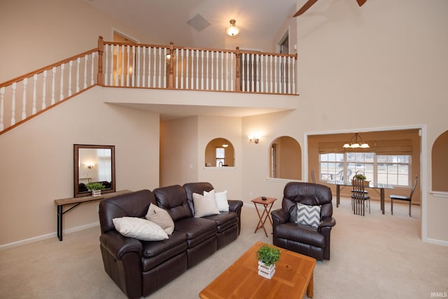 carpeted living room featuring arched walkways, baseboards, a towering ceiling, and an inviting chandelier