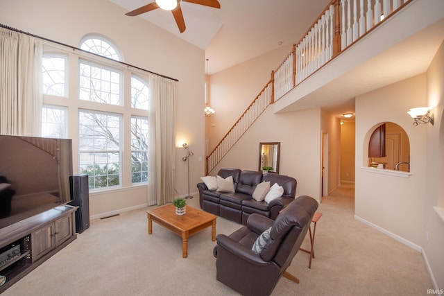 carpeted living area featuring visible vents, stairway, a towering ceiling, and baseboards