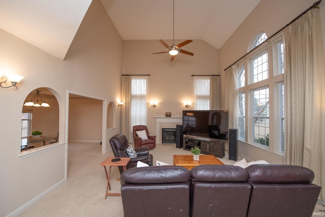 living area with a healthy amount of sunlight, a fireplace, high vaulted ceiling, and light colored carpet