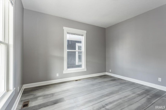 spare room with visible vents, baseboards, and wood finished floors