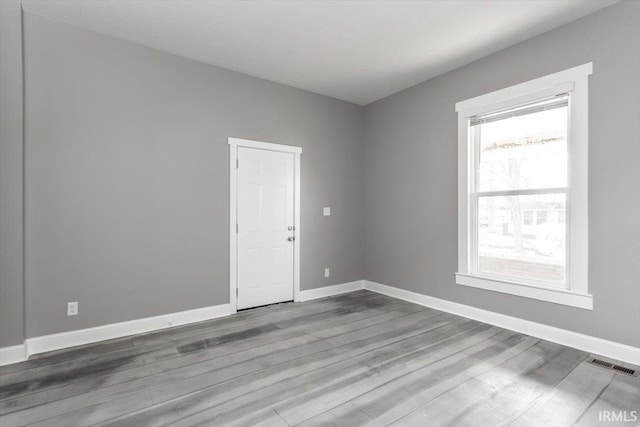 unfurnished room with visible vents, baseboards, and wood finished floors