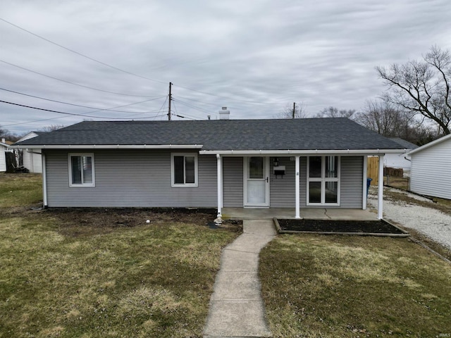 view of front of home featuring covered porch, a shingled roof, and a front lawn