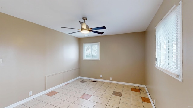 empty room featuring ceiling fan, visible vents, baseboards, and light tile patterned flooring