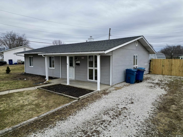 exterior space featuring a patio, a shingled roof, gravel driveway, and fence