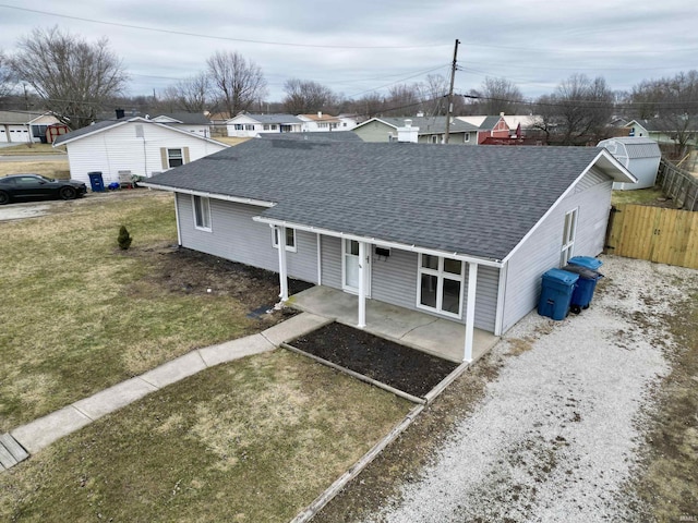 single story home with a shingled roof, gravel driveway, fence, a patio area, and a front lawn