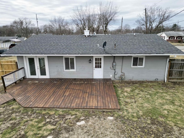 back of property with fence, french doors, a lawn, roof with shingles, and a wooden deck