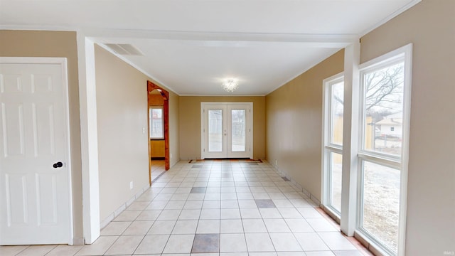 doorway featuring light tile patterned floors, plenty of natural light, visible vents, and crown molding