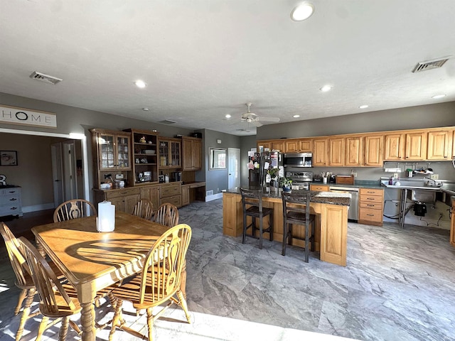 kitchen featuring a kitchen breakfast bar, appliances with stainless steel finishes, visible vents, and a center island