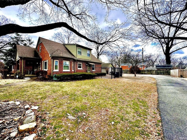 view of property exterior featuring a yard, fence, and brick siding