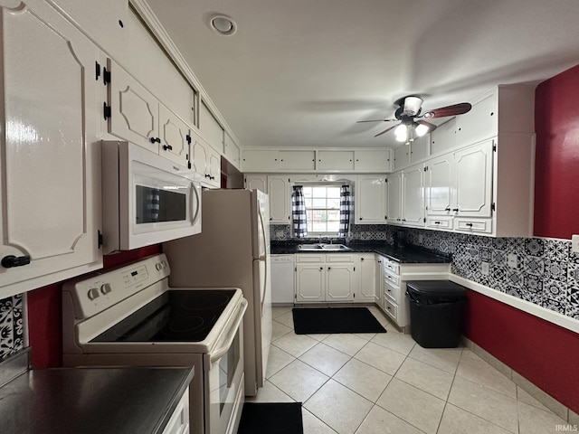 kitchen with white appliances, white cabinetry, a sink, and light tile patterned floors