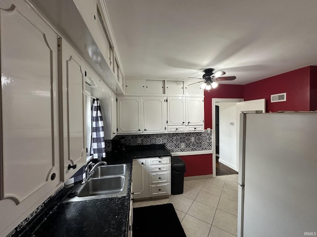 kitchen featuring visible vents, freestanding refrigerator, white cabinets, a sink, and light tile patterned flooring