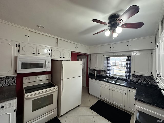 kitchen with white appliances, white cabinets, dark countertops, a sink, and light tile patterned flooring