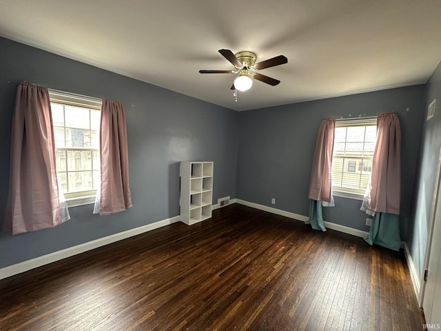 unfurnished room featuring dark wood-type flooring, a wealth of natural light, and baseboards