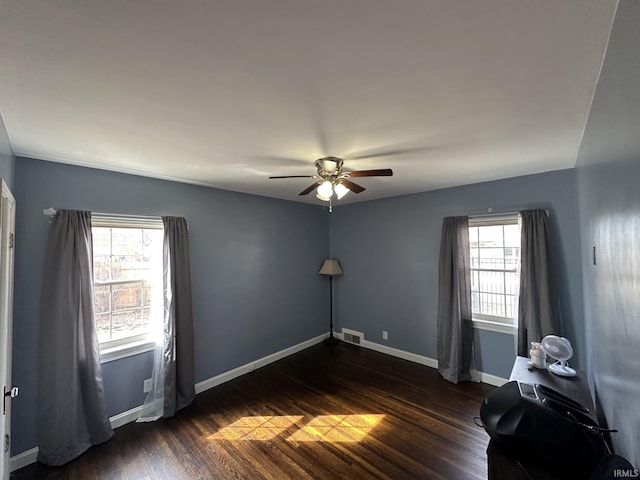 unfurnished room with dark wood-type flooring, a ceiling fan, visible vents, and baseboards