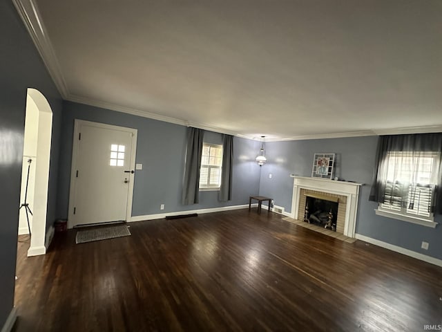 unfurnished living room featuring arched walkways, crown molding, a fireplace, wood finished floors, and baseboards