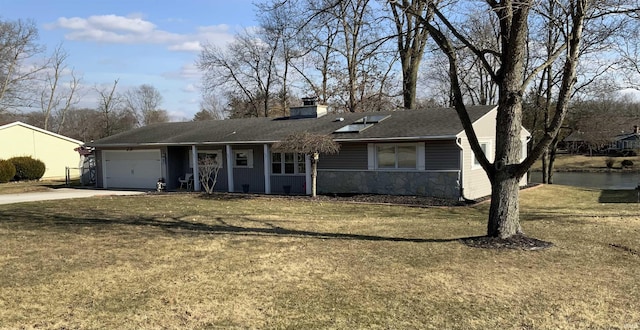 ranch-style house with a chimney, an attached garage, stone siding, driveway, and a front lawn