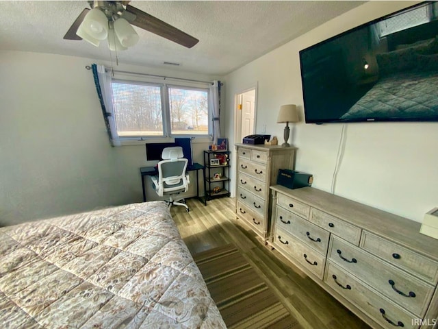 bedroom featuring visible vents, dark wood finished floors, a textured ceiling, and ceiling fan