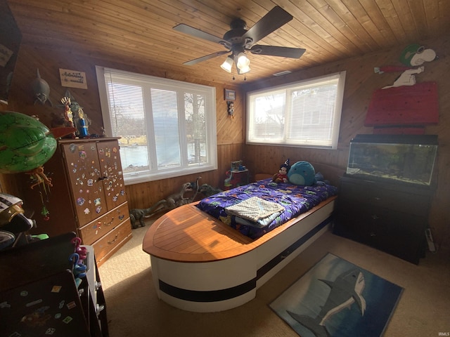 carpeted bedroom with wooden ceiling, wooden walls, and a ceiling fan