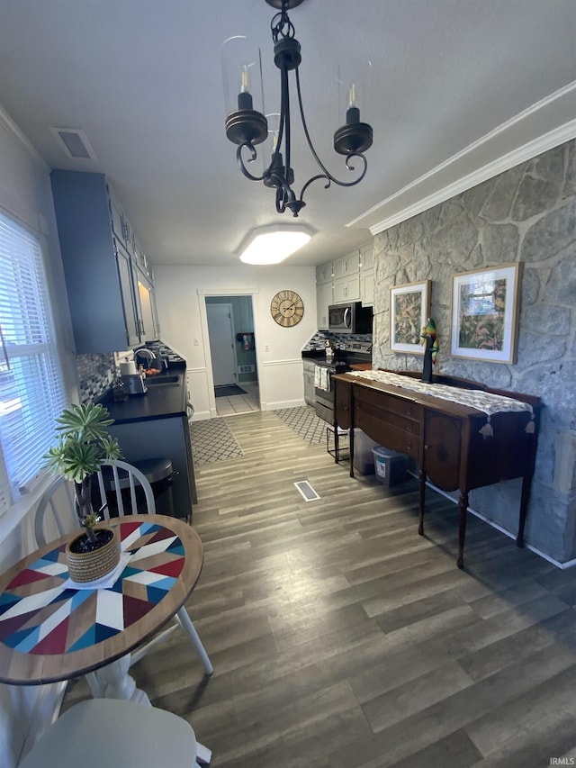 dining area featuring visible vents, crown molding, an inviting chandelier, and wood finished floors