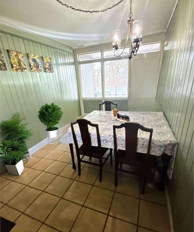 tiled dining area with an inviting chandelier and baseboards