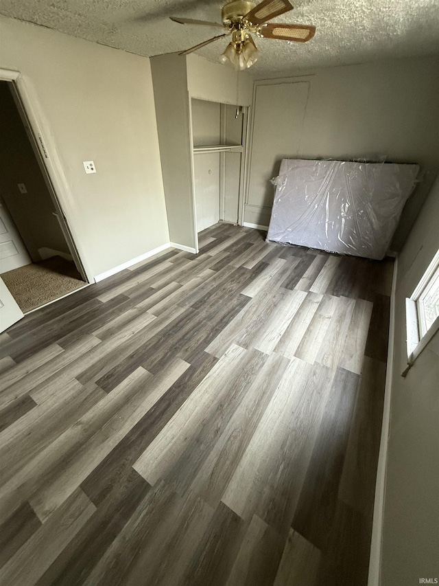 unfurnished bedroom featuring a textured ceiling, a ceiling fan, and wood finished floors