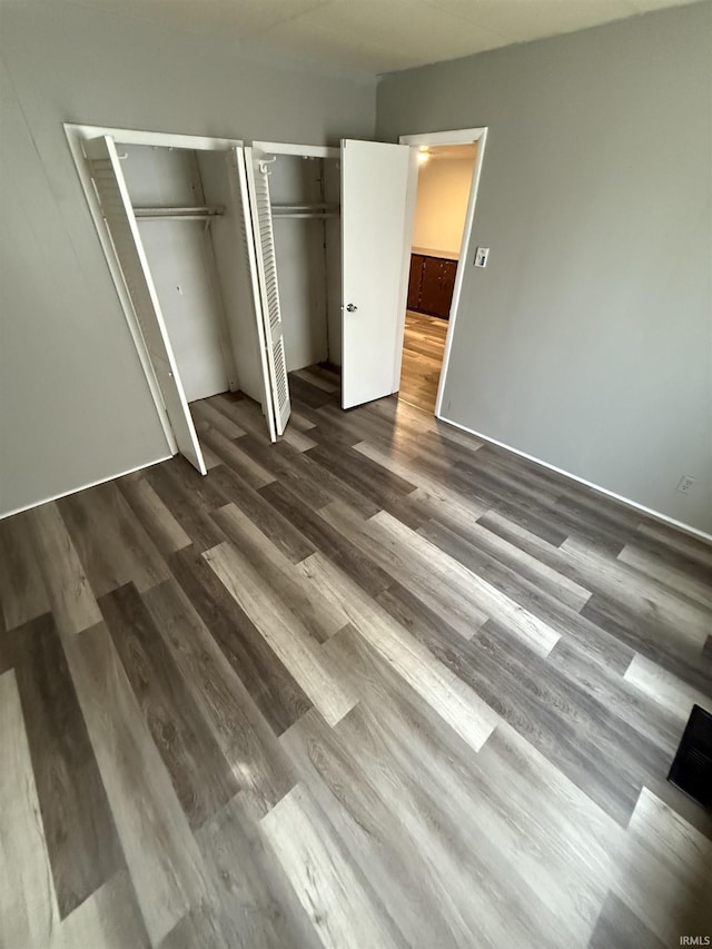 unfurnished bedroom with dark wood-style flooring and two closets