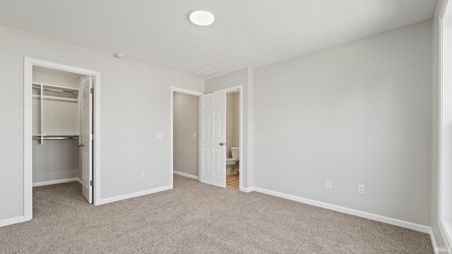 unfurnished bedroom featuring carpet floors, a spacious closet, and baseboards