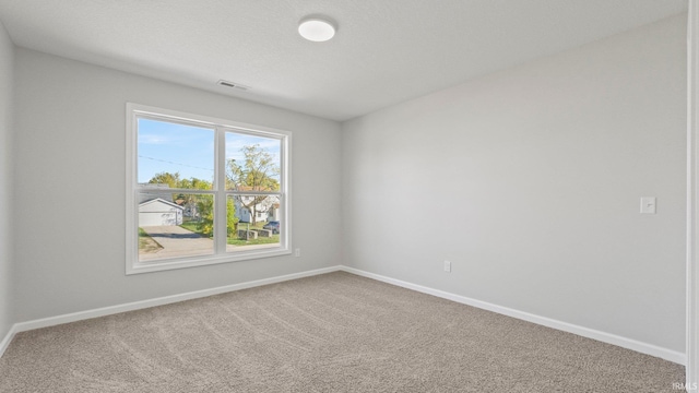 spare room featuring baseboards, a textured ceiling, visible vents, and carpet flooring