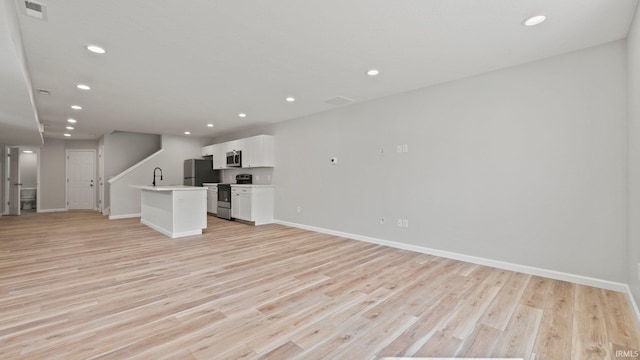 unfurnished living room featuring recessed lighting, a sink, visible vents, baseboards, and light wood-type flooring