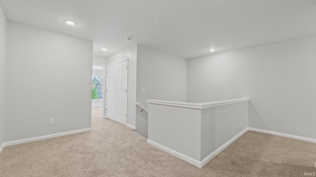 hallway with carpet, baseboards, an upstairs landing, and recessed lighting